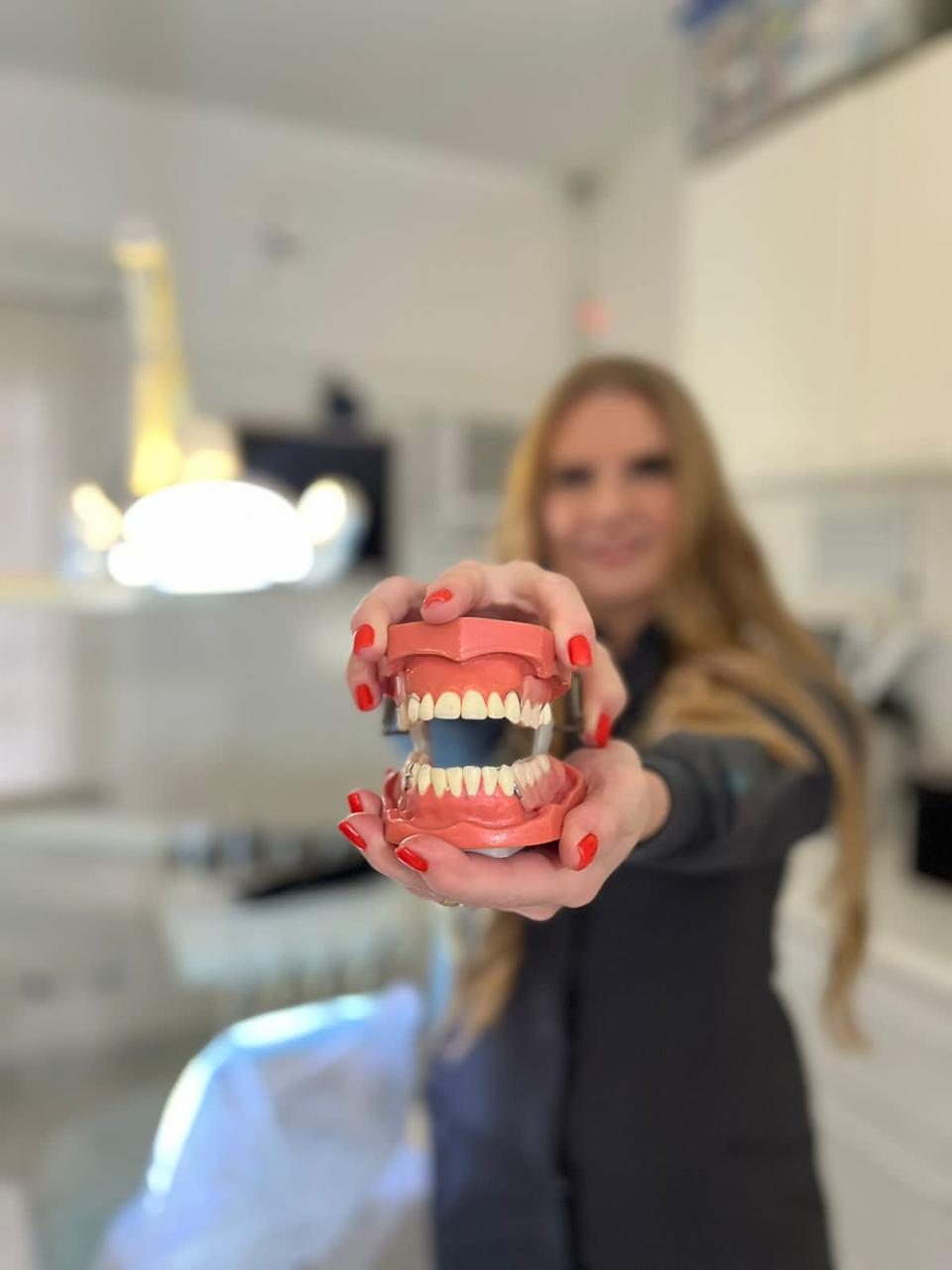 Dra. Cinthya Bittar segurando um modelo odontológico de arcada dentária